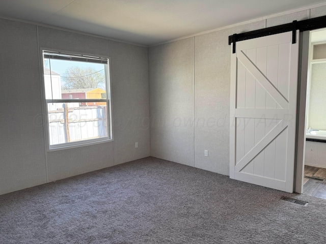6 Honeywood Pl, Dalhart, TX 79023 - unfurnished bedroom with ornamental molding, a barn door, visible vents, and carpet floors