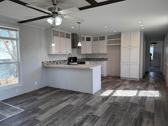6 Honeywood Pl, Dalhart, TX 79023 - kitchen with dark wood-type flooring, a peninsula, wall chimney range hood, white cabinets, and black electric range