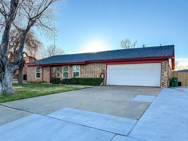 single story home featuring a garage, a front yard, concrete driveway, and brick siding