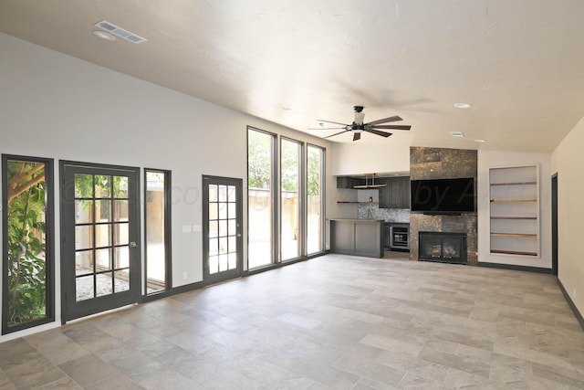 3801 Deann Dr, Amarillo, TX 79121 - unfurnished living room featuring ceiling fan, a tiled fireplace, vaulted ceiling, built in features, and light stone finish floors