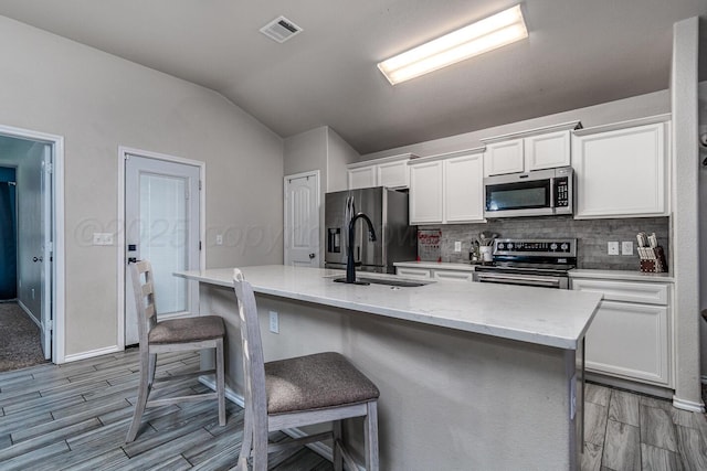 606 Elgin St, Amarillo, TX 79118 - kitchen featuring stainless steel appliances, a sink, white cabinets, decorative backsplash, and vaulted ceiling