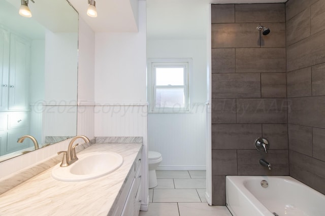 full bath with toilet, wainscoting, vanity,  shower combination, and tile patterned floors