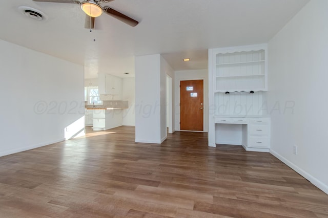 unfurnished living room with ceiling fan, wood finished floors, visible vents, and baseboards