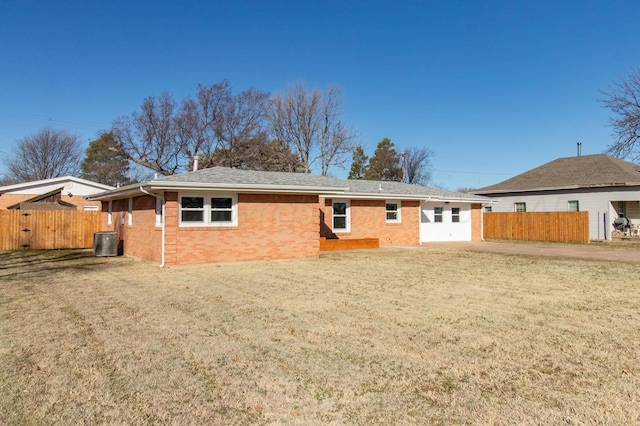 rear view of house with central AC, fence, brick siding, and a lawn