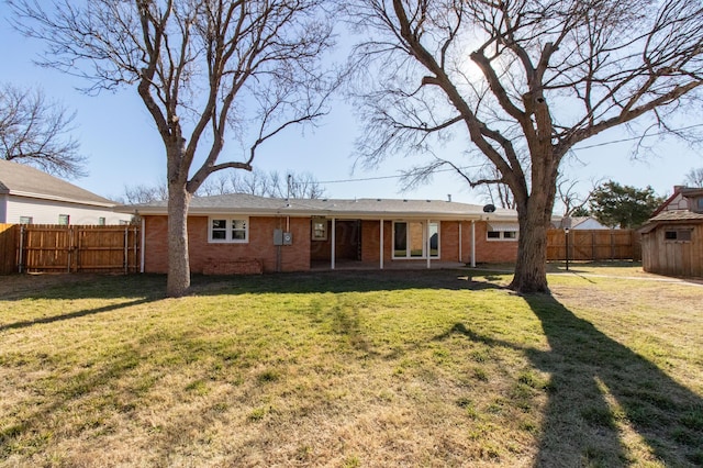 rear view of property with brick siding, a yard, a patio area, a fenced backyard, and an outdoor structure