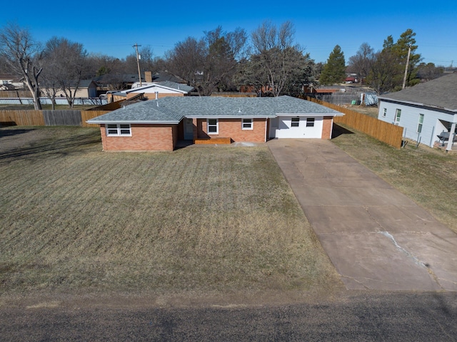 view of front of property featuring driveway, a shingled roof, fence, a front yard, and brick siding