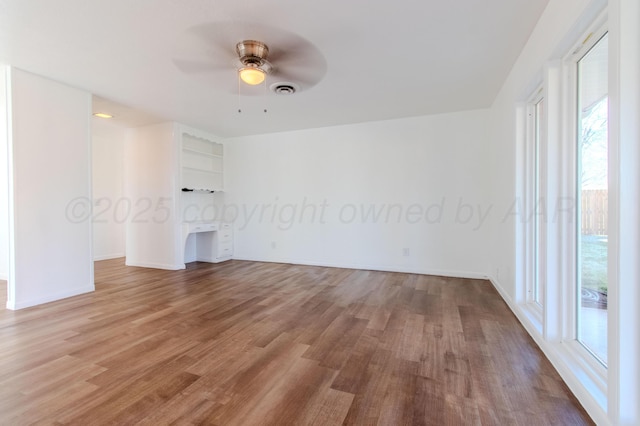 empty room with ceiling fan, wood finished floors, and visible vents