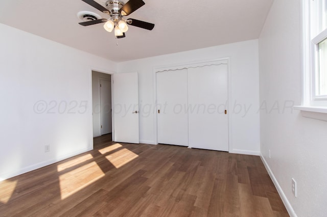 unfurnished bedroom featuring dark wood-style floors, a closet, a ceiling fan, and baseboards