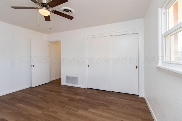 unfurnished bedroom featuring multiple windows, visible vents, and wood finished floors