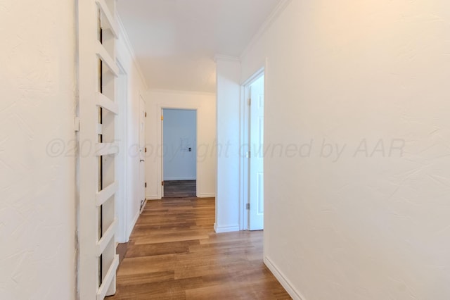 corridor with baseboards, ornamental molding, and wood finished floors