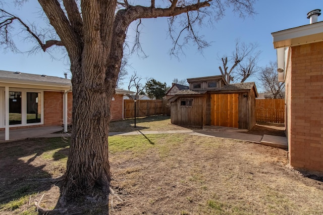 view of yard with a patio area, a fenced backyard, and an outbuilding