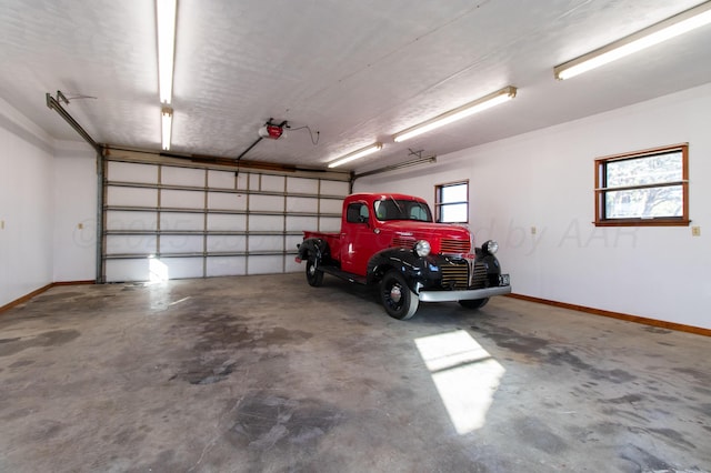 parking garage featuring baseboards and a garage door opener