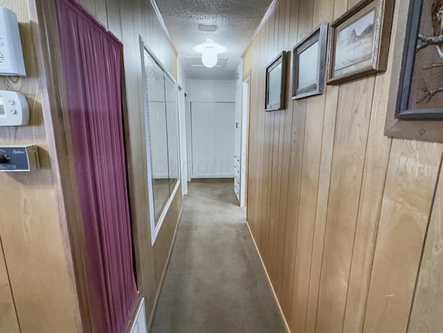 hall with wooden walls, carpet flooring, and a textured ceiling