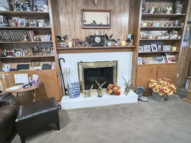 carpeted living room with wooden walls and a fireplace