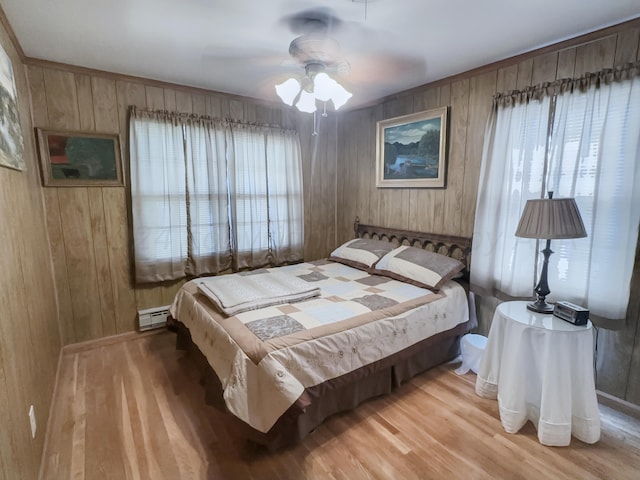 bedroom with hardwood / wood-style floors, wooden walls, multiple windows, and ceiling fan