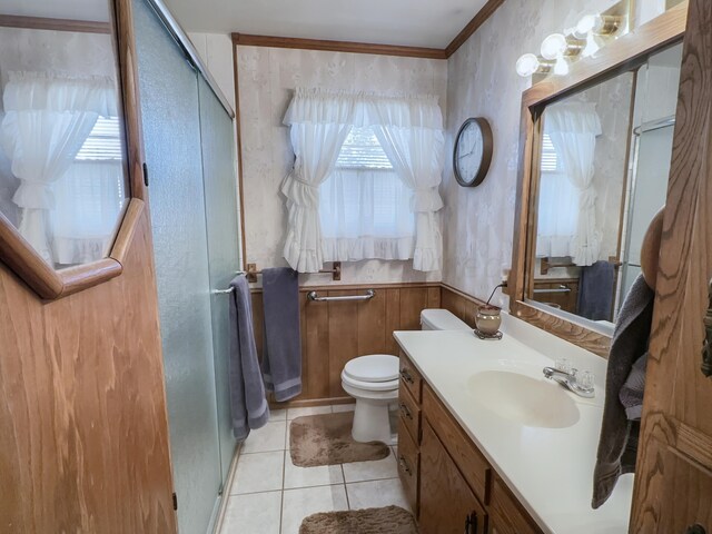 bathroom featuring a shower with door, crown molding, vanity, tile patterned flooring, and toilet