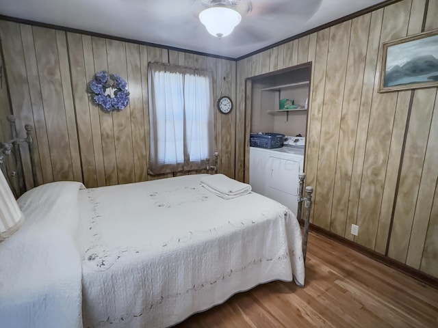 bedroom featuring wood walls, ceiling fan, hardwood / wood-style floors, and separate washer and dryer