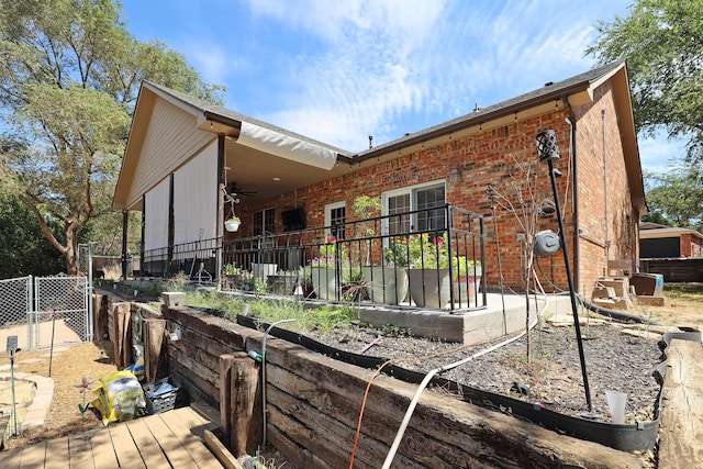 back of house with brick siding, fence, and ceiling fan