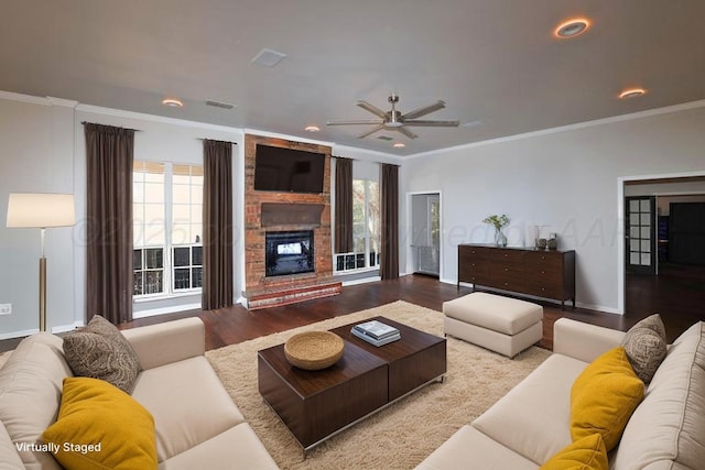 living area with ceiling fan, a fireplace, a wealth of natural light, and ornamental molding