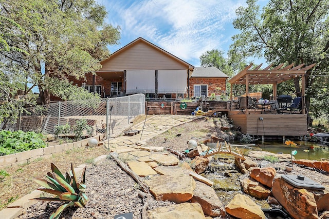 back of property with fence, a pergola, brick siding, and a deck
