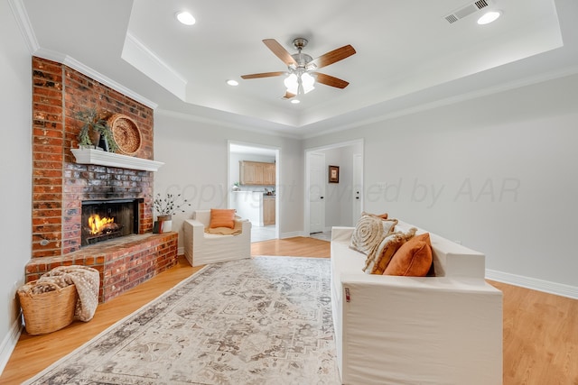 6100 Mckay Ct, Amarillo, TX 79118 - living room featuring a raised ceiling, light wood-style floors, crown molding, ceiling fan, and a fireplace