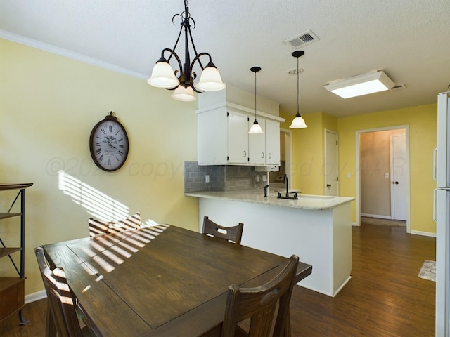 dining space with sink, dark hardwood / wood-style flooring, ornamental molding, a textured ceiling, and an inviting chandelier