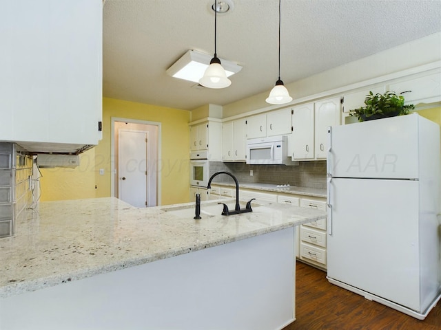 kitchen featuring sink, white appliances, light stone counters, white cabinets, and decorative light fixtures