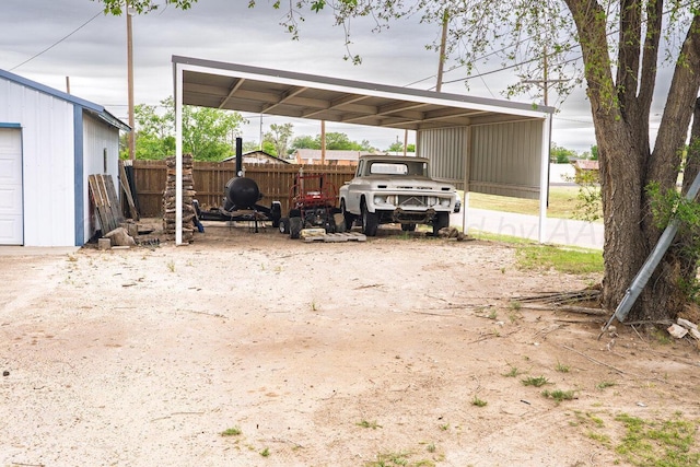 view of parking featuring fence and a carport