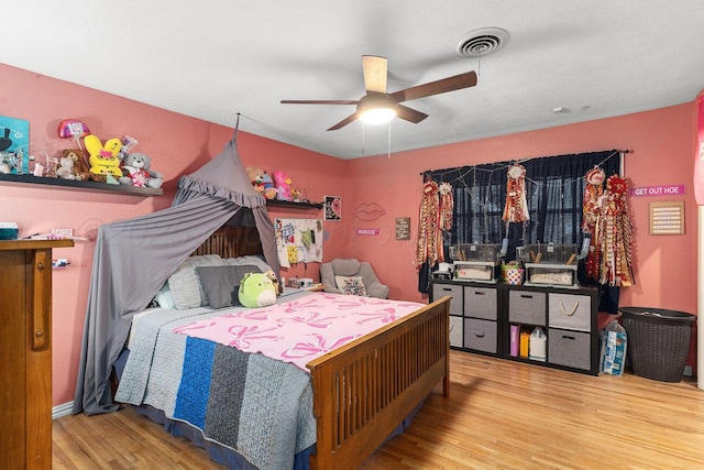 bedroom with a ceiling fan, visible vents, and wood finished floors