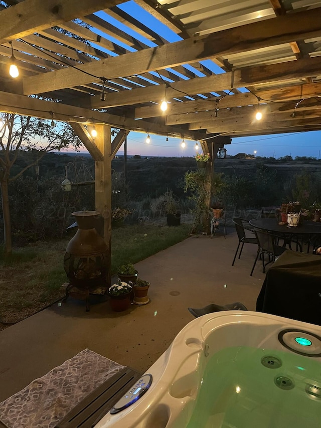 patio terrace at dusk with a pergola and a hot tub