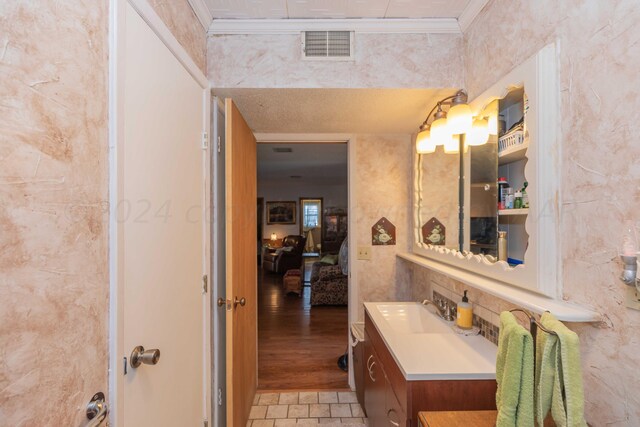 bathroom with vanity, hardwood / wood-style flooring, and crown molding