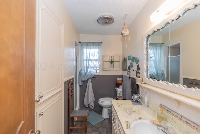 bathroom with toilet, decorative backsplash, a textured ceiling, vanity, and walk in shower