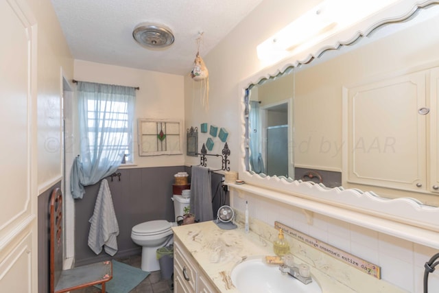 bathroom with vanity, toilet, and a textured ceiling