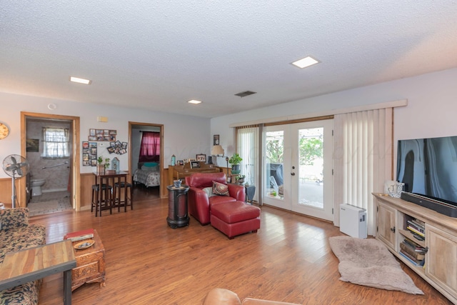 living room with french doors, light hardwood / wood-style flooring, and a textured ceiling