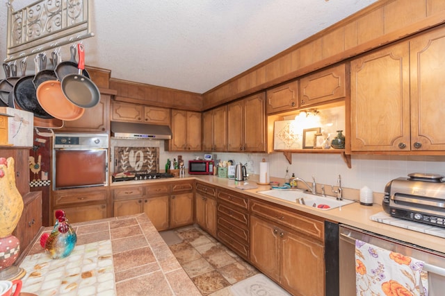 kitchen featuring a textured ceiling, stainless steel appliances, sink, and tasteful backsplash