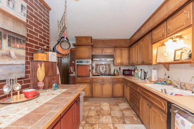 kitchen with a textured ceiling, appliances with stainless steel finishes, sink, and tasteful backsplash