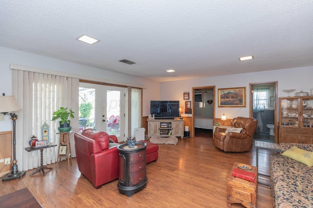 living room with a textured ceiling, wood-type flooring, french doors, and plenty of natural light