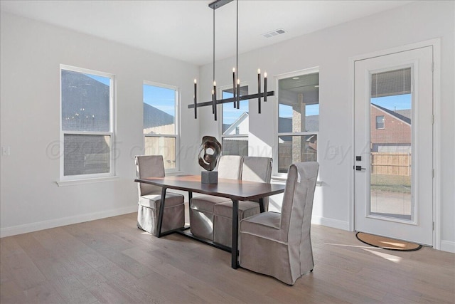 dining space with baseboards, wood finished floors, visible vents, and a notable chandelier