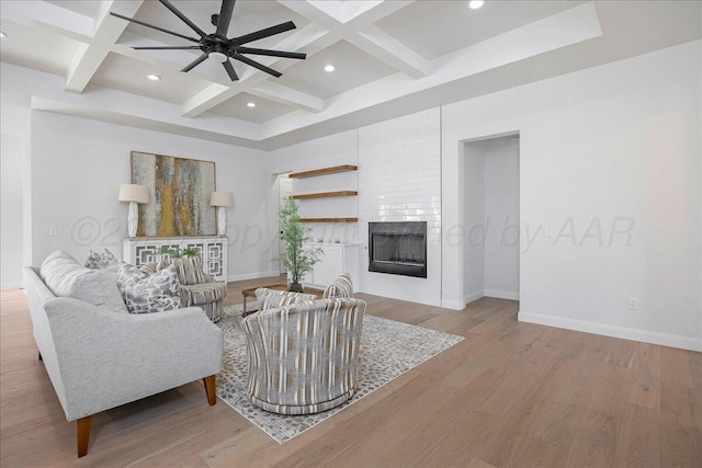 living area featuring light wood-type flooring, a fireplace, coffered ceiling, and beamed ceiling