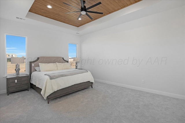 carpeted bedroom with a tray ceiling, wooden ceiling, visible vents, and baseboards