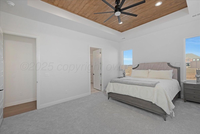 carpeted bedroom featuring wooden ceiling, baseboards, multiple windows, and a tray ceiling