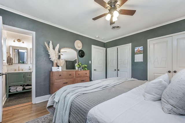 501 Sunset Ter, Amarillo, TX 79106 - bedroom featuring multiple closets, wood finished floors, crown molding, a sink, and ceiling fan