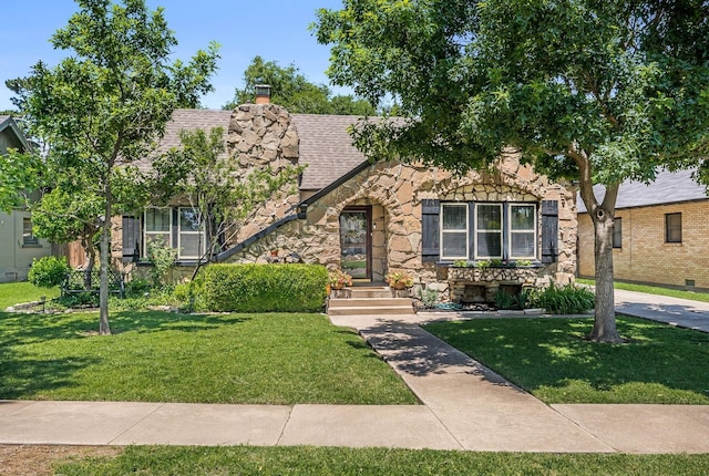 501 Sunset Ter, Amarillo, TX 79106 - english style home featuring stone siding, a front yard, a shingled roof, and a chimney