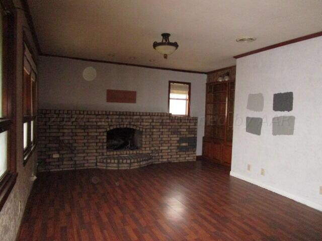 unfurnished living room with a fireplace, dark wood-type flooring, and ornamental molding