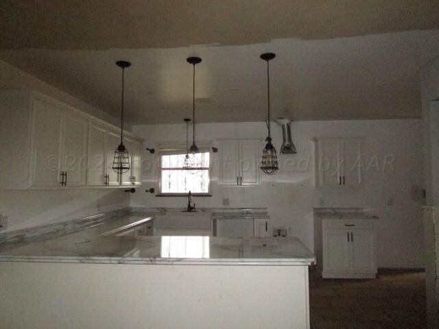 kitchen with white cabinets, sink, pendant lighting, and kitchen peninsula