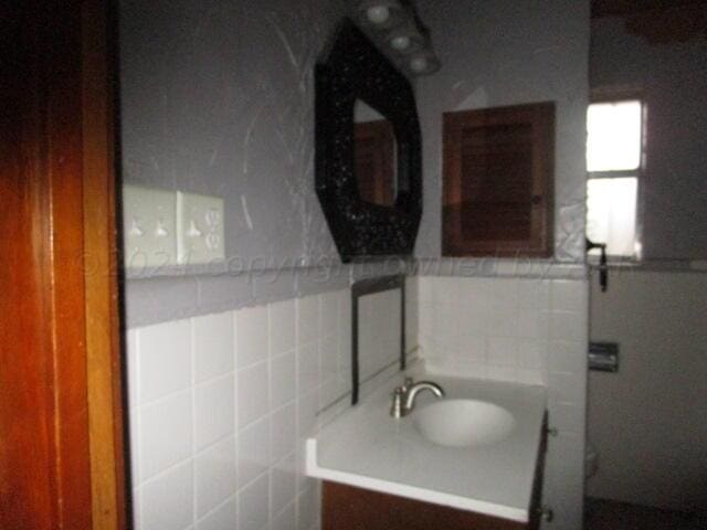 bathroom featuring tile walls, vanity, and toilet