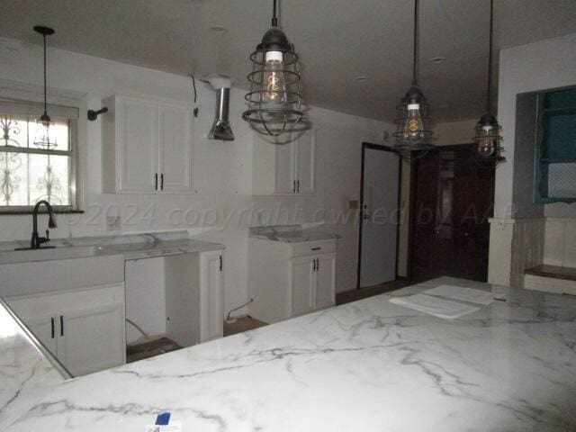 kitchen featuring white cabinets, pendant lighting, and light stone countertops