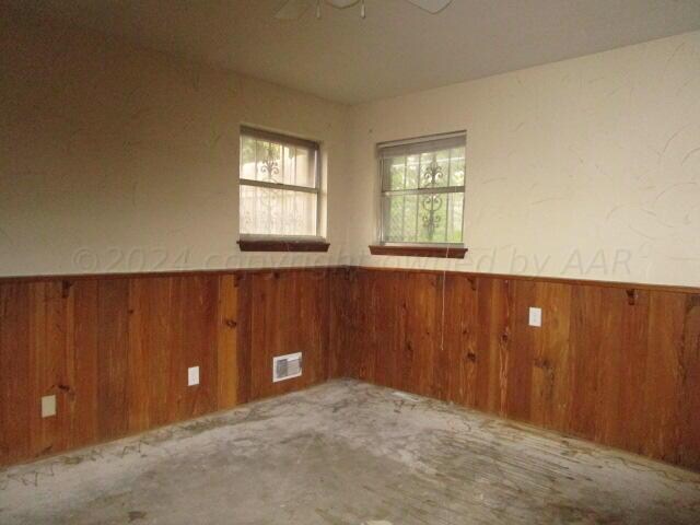 empty room with ceiling fan and wooden walls