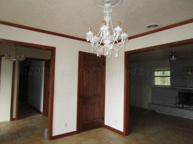 unfurnished dining area featuring an inviting chandelier, crown molding, and a textured ceiling