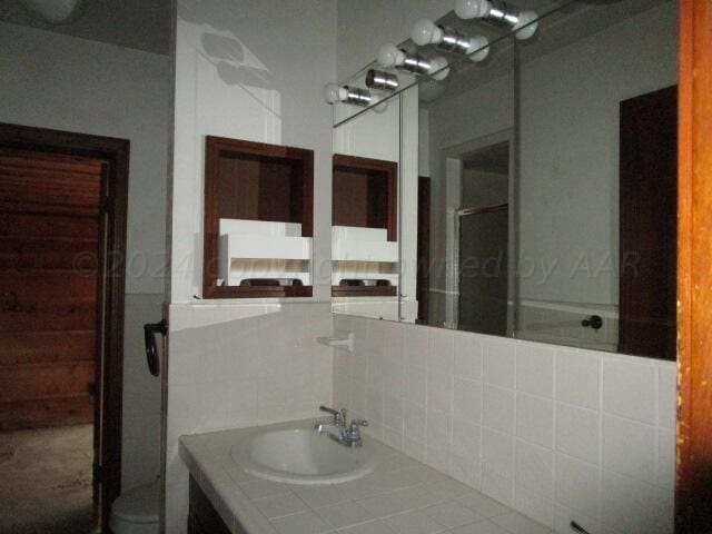 bathroom featuring vanity, an enclosed shower, and decorative backsplash